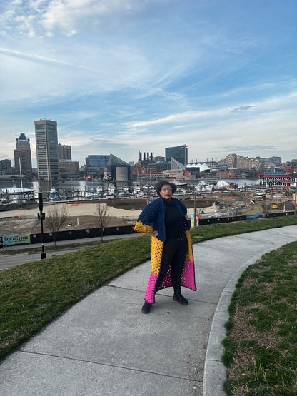 Person standing on a sidewalk with a cityscape in the background