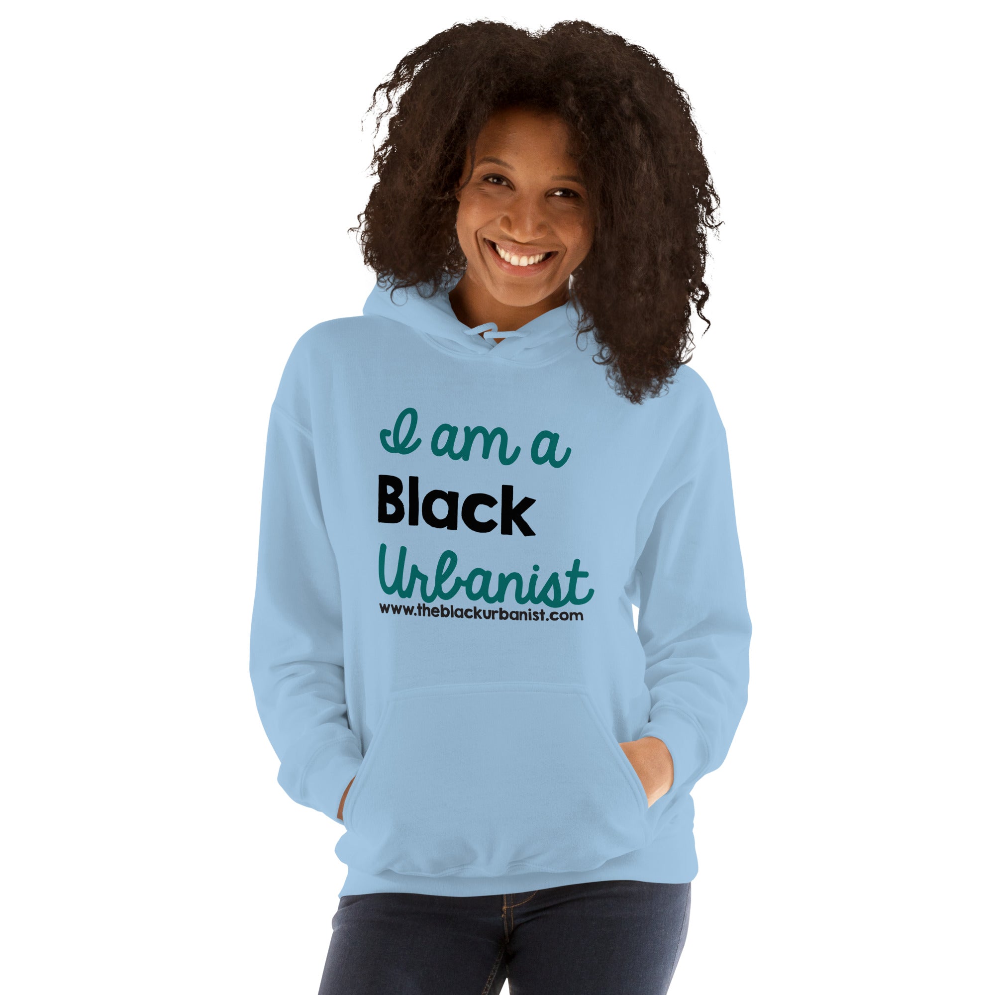 Black woman with loose curly hair in a light blue hoodie with the words I am a Black Urbanist printed on it