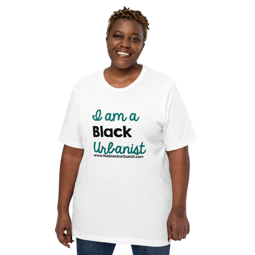 Dark-skinned Black woman with short natural hair wears t-shirt with I Am A Black Urbanist printed on it